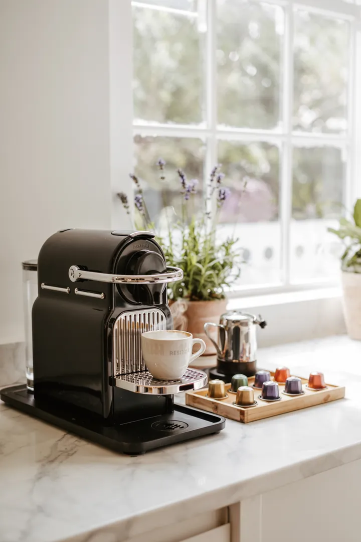 Elegante Kaffeebereiter und stilvolle Tassenaufbewahrung in einer modernen Küchenumgebung mit offenen Regalen für ein einladendes Ambiente.