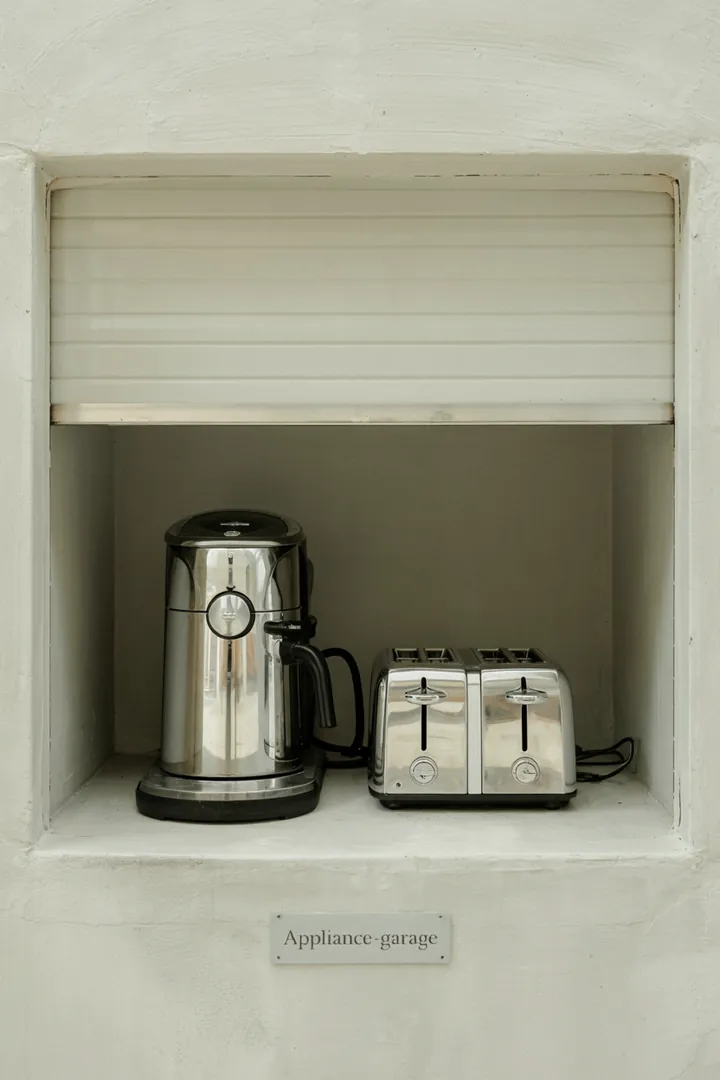 Appliance-Garage mit Rolltür, Kaffeemaschine und Toaster ordentlich verstaut, helle Küche. Deutliche Details, gut erkennbar; küche aufbewahrung geräte im Fokus, screenreader-freundlich beschrieben.