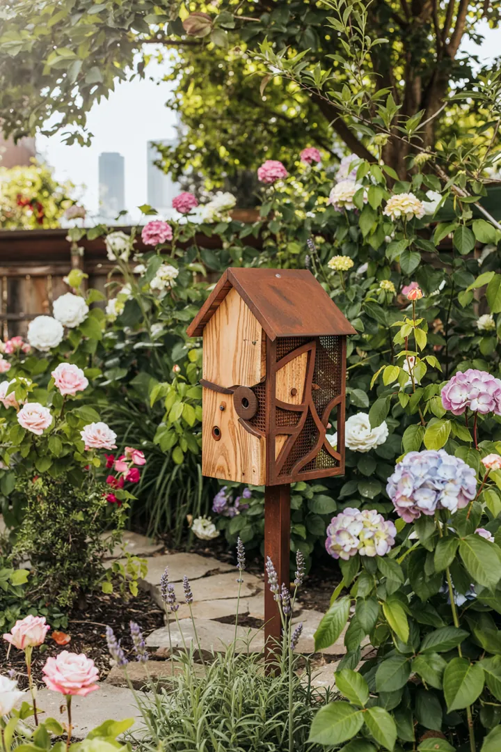 Ein liebevoll gestaltetes Zuhause für Vögel, umgeben von bunten Blumen und grünen Ästen, inspiriert kreative Vogelhaus Ideen.