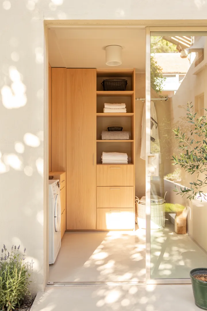 Ein heller Raum mit praktischer Waschstation und elegantem Zugang, der eine moderne Waschküche hinter Schiebetür schafft.