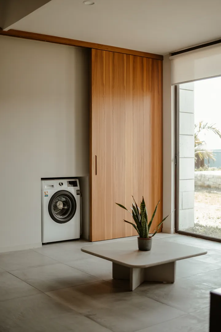 Ein moderner Waschraum mit elegant versteckter Waschmaschine hinter einer stilvollen Schiebetür, die optimalen Platz bietet und das Gesamtbild harmonisch ergänzt.