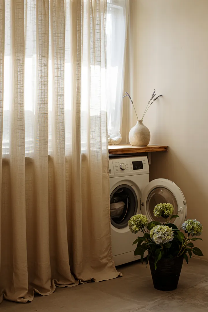 Hinter einem blickdichten Stoff verbirgt sich ein modernes Haushaltsgerät, das für Sauberkeit sorgt und Wäschepflege erleichtert.