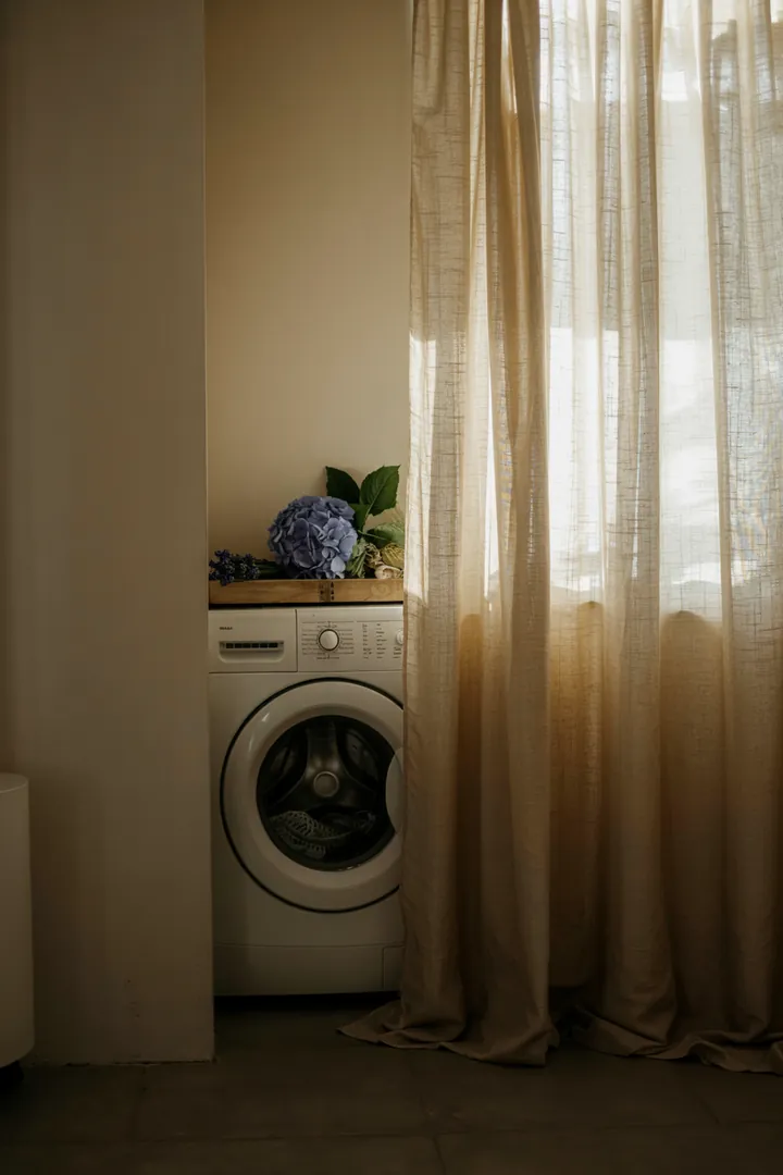 Ein schicker Raum mit einem eleganten Vorhang, hinter dem eine moderne Waschmaschine verborgen ist, die für Funktionalität und Stil sorgt.