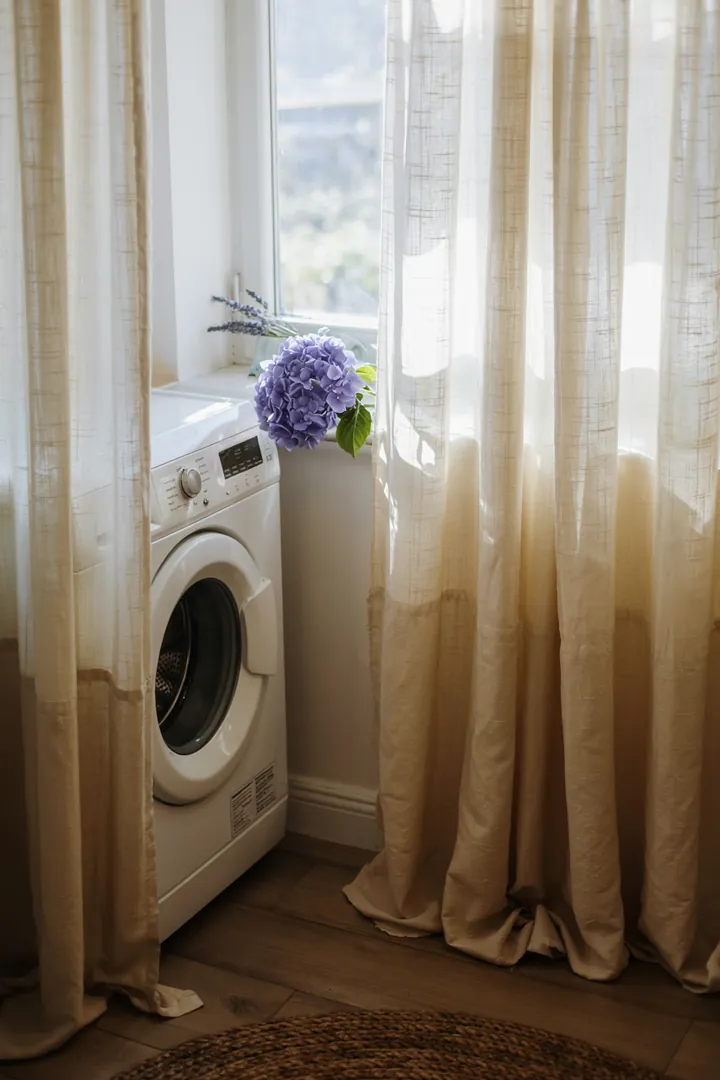 Ein verstecktes Haushaltsgerät hinter einem eleganten Stoff, das für frische Wäsche sorgt und den Alltag erleichtert. Ideal für kleine Räume.