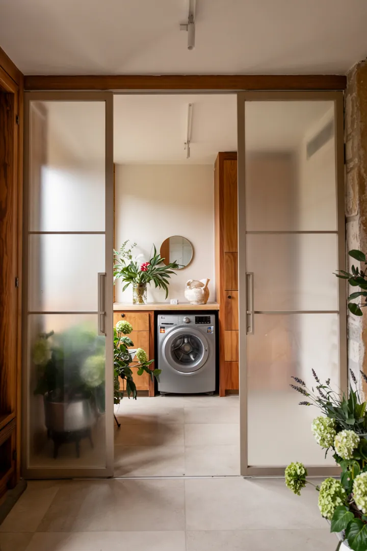 Ein stilvoller Flur mit einem cleveren Möbelstück, das eine moderne Waschmaschine integriert, um den Raum aufgeräumt und funktional zu gestalten.