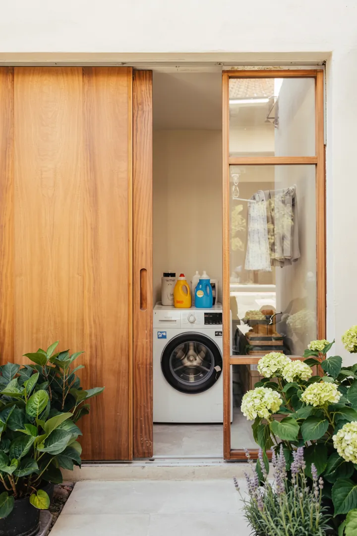 Ein sauberer, funktionaler Raum mit einer geschickt integrierten Waschmaschine, die unauffällig in einer Abstellkammer platziert ist, bietet praktische Lösungen für den Alltag.