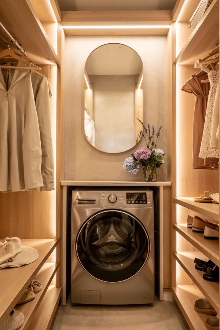 Ein stilvoll eingerichteter Raum, in dem eine moderne Waschmaschine geschickt in einer Garderobe verborgen ist, um Platz und Ordnung zu schaffen.