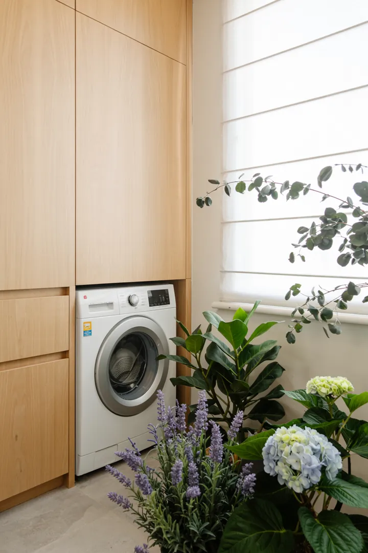 Ein eleganter Raum mit einer cleveren Lösung, bei der ein Haushaltsgerät hinter einer stilvollen Möbeltür verborgen ist, um die Ästhetik zu wahren.