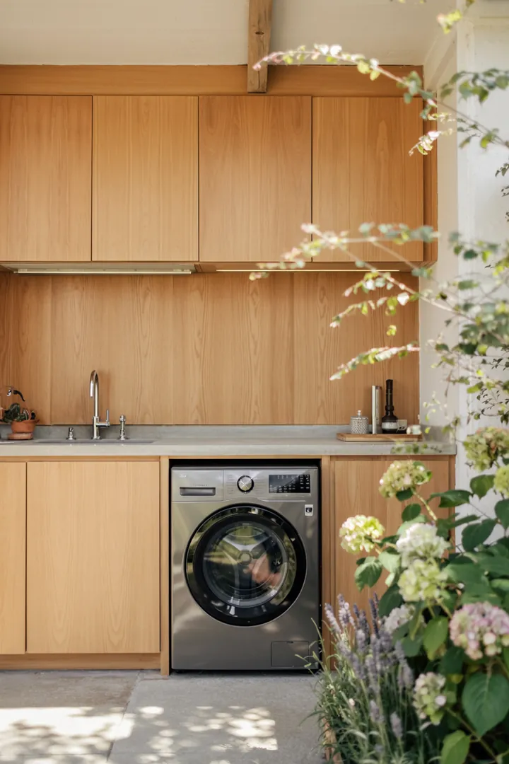 Ein moderner, eleganter Raum zeigt ein heimisches Waschgerät, das geschickt in die Küchenmöbel integriert ist, um Platz zu sparen und eine harmonische Gestaltung zu fördern.