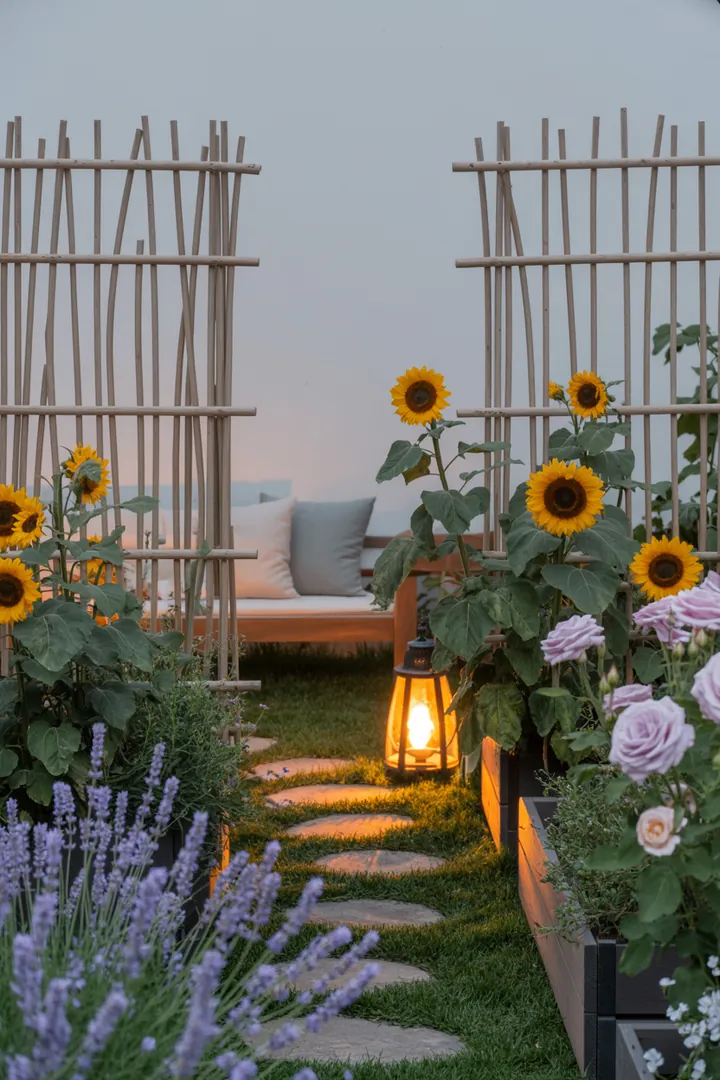 Elegante Gartenlandschaft mit schmalen Pflanzkübeln, einem dekorativen Rankgitter, Sichtschutzmatten, stilvollen Trittplatten und einer praktischen Mülltonnenbox, ergänzt durch moderne Außenleuchten.